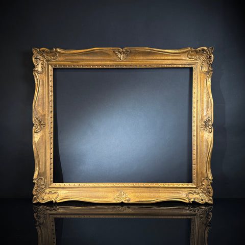 A large ornate carved gilt wood French vintage picture frame without a backing, displayed against a dark background.